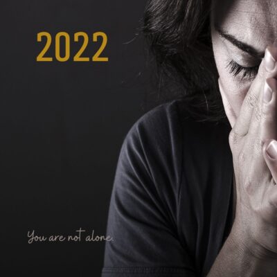 The year "2022" superimposed over a closeup photo of a person holding their face in their hands