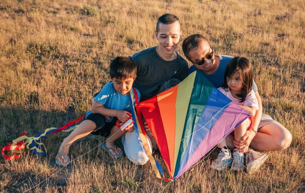 Two parents and two children with a rainbow-patterned kite